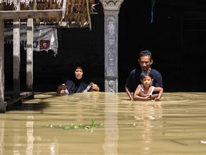 A family walks through a flooded residential area in Gampong Meunasah, Indonesia.