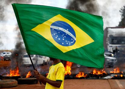 En el bloqueo de Planaltina, un hombre con la playera de la "seleçao" y la bandera brasileña: símbolos que se ha apropiado el bolsonarismo.