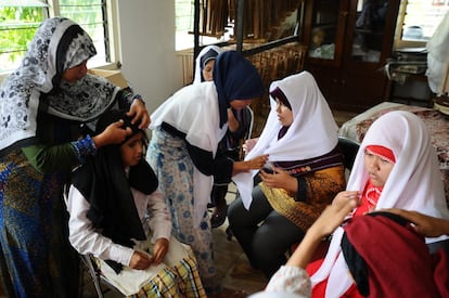 Las alumnas de la escuela se colocan pañuelos blancos antes de comenzar la lectura del Corán en braille.