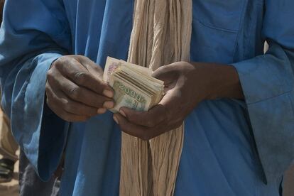 Un contrabandista cuenta su dinero mientras los inmigrantes suben a los camiones para dirigirse al norte hacia Argelia en el puesto fronterizo de Assamaka, en el norte de Níger, el domingo 3 de junio de 2018. 