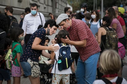 Unos padres acarician a su hija antes de la entrada en clase, este lunes, en la escuela infantil y primaria Xirinacs, en el barrio del Eixample Esquerra de Barcelona. / Massimiliano Minocri