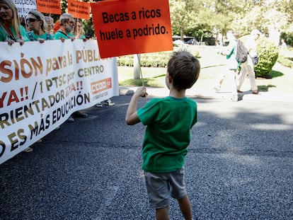 Un niño porta un cartel que reza "Becas a ricos huele a podrido" durante una manifestación por la educación pública en la Comunidad de Madrid, el 10 de septiembre de 2022.