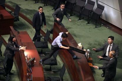 Los oficiales de seguridad persiguen al legislador prodemocrático Au Nok-hin, mientras salta por los escritorios para perseguir al presidente ejecutivo de Hong Kong, Carrie Lam, tras una sesión de preguntas y respuestas con los legisladores en el Consejo Legislativo de Hong Kong.
