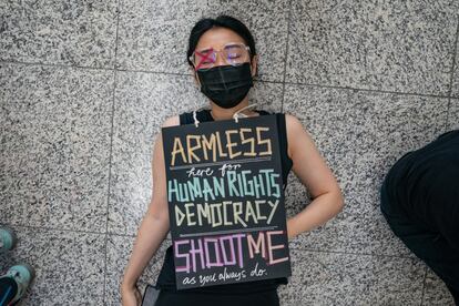 Una manifestante se tumba en el suelo del aeropuerto con un cartel que lee 'Inofensivo. Por la democracia de los derechos humanos. Dispárenme como siempre hacen', el 12 de agosto de 2019.