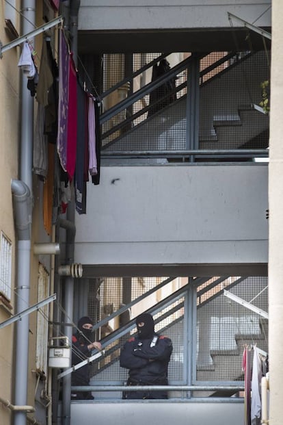 Dos agentes vigilan desde uno de los edificios que han sido registrados durante la operación.