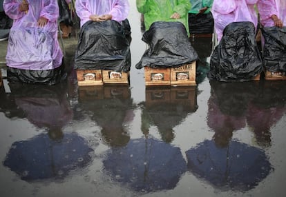 Varios manifestantes, con sus pies sumergidos en cemento, se encuentran bajo la lluvia durante una manifestación frente al palacio presidencial en Yakarta, Indonesia.