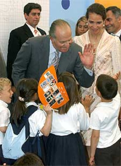 Don Juan Carlos, junto a su hija Elena, saludan a unos niños en la Feria del Libro, de la que se ha llevado poemas del 11-M, literatura infantil y las memorias de Guerra.