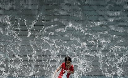 Una ni&ntilde;a juega en una catarata artificial en Kuala Lumpur (Malasia). El pa&iacute;s est&aacute; experimentado ahora un tiempo muy caluroso y seco.