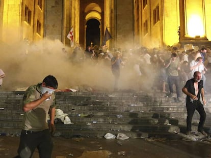 Manifestantes se protegen de una carga de gases lacrimógenos, este viernes en Tblisi.