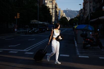 Una joven con la mascarilla en la mano cruza un paso de cebra, en el centro de Barcelona. La orden del Ministerio de Sanidad mantiene, no obstante, la obligatoriedad del uso de la mascarilla al aire libre cuando se produzcan aglomeraciones y no se pueda mantener una distancia mínima de 1,5 metros de distancia entre personas, salvo grupos de convivientes.