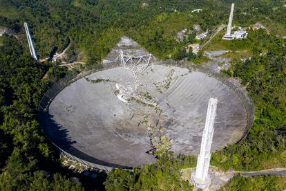 This aerial view shows the damage at the Arecibo Observatory after one of the main cables holding the receiver broke in Arecibo, Puerto Rico, on December 1, 2020. - The radio telescope in Puerto Rico, which once starred in a James Bond film, collapsed Tuesday when its 900-ton receiver platform fell 450 feet (140 meters) and smashed onto the radio dish below. (Photo by Ricardo ARDUENGO / AFP)
