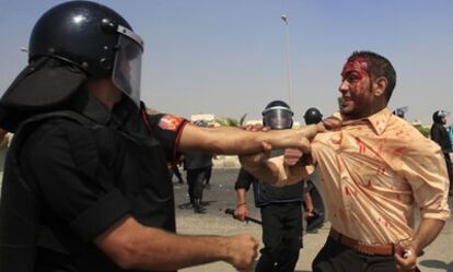 Un policía antidisturbio se enfrenta a un manifestante contrario a Mubarak herido durante los disturbios en El Cairo.