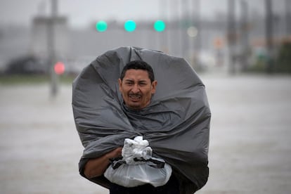 Un hombre utiliza una bolsa de basura para cubrirse de la lluvia, el 28 de agosto de 2018 al este de Houston.  