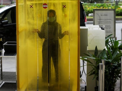 Una trabajadora pasa por una cámara desinfectante a la entrada del centro comercial Senayan City en Yakarta, Indonesia. Las tiendas se preparan para reabrir después de que el gobierno indonesio haya comenzado a aliviar las restricciones por el coronavirus en un esfuerzo por reactivar la economía.