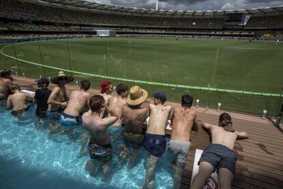 Un grupo de espectadores observa un partido de cricket desde el interior de una piscina en Brisbane (Australia).