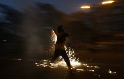 Un corredor lleva fuegos artificiales mientras participa en la fiesta de 'Correfoc' (correr con fuego) durante la noche de San Juan en Barcelona.