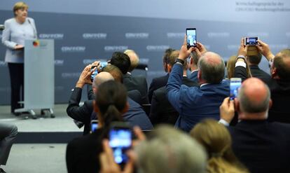 Un grupo de periodistas toman fotos con sus móviles mientras la canciller alemana Angela Merkel ofrece una rueda de prensa en Berlín.