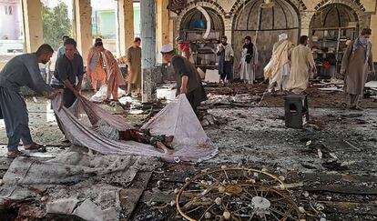 Un grupo de hombres se prepara para llevar el cuerpo de una víctima dentro de una mezquita chiíta tras el atentado con bomba que se ha producido en Kunduz (Afganistán).