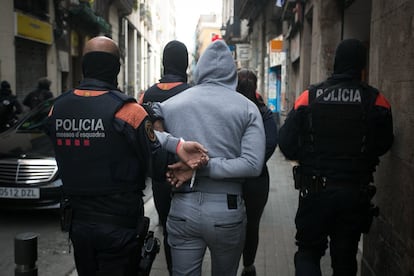 Algunos 'mossos' custodian a uno de los detenidos hasta el vehiculo policiales.