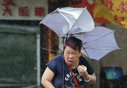 Una mujer come mientras intenta controlar su paraguas debido a las poderosas ráfagas de viento generadas por el tifón Megi en la Isla de Taipei (Taiwán). 
