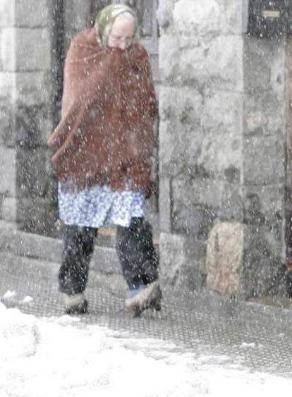 Una vecina de Pajares (Asturias) camina por la calle en medio del temporal.