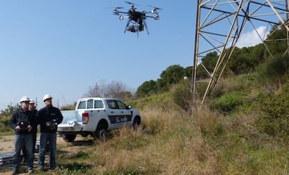 Unos operarios de Endesa supervisan los trabajos de comprobaci&oacute;n de un dron.