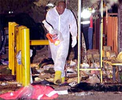 Un policía busca pistas junto a los destrozos causados por el atentado suicida de la estación de tren israelí.