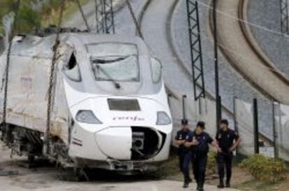 Efectivos de la policía custodian la locomotora del tren Alvia que el pasado miércoles descarriló en las inmediaciones de Santiago, antes de ser trasladada a Escravitude, en Padrón (A Coruña), a una zona custodiada por la Policía Nacional. EFE/Lavandeira jr