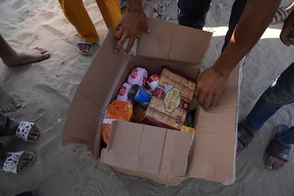 Gazatíes abren una caja con alimentos y paquetes de ayuda humanitaria entregados por la Fundación Humanitaria de Gaza en Rafah este martes.