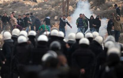 Jovenes palestinos del campo de refugiados de al-Jalazoun se enfrentan a la policía palestina en el bloqueo de una carretera.