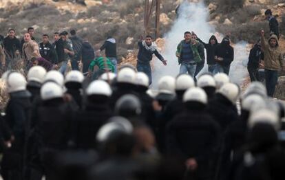 Jovenes palestinos del campo de refugiados de al-Jalazoun se enfrentan a la polic&iacute;a palestina en el bloqueo de una carretera.