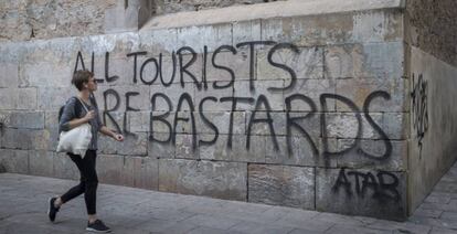 Una mujer pasa frente a una pintada contra el turismo, en Barcelona