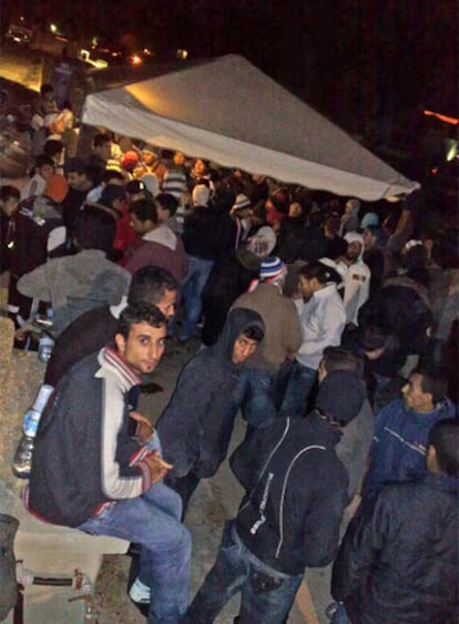 Un grupo de inmigrantes espera en el puerto tras ser desembarcados por la policía en la costa de Lampedusa, Italia