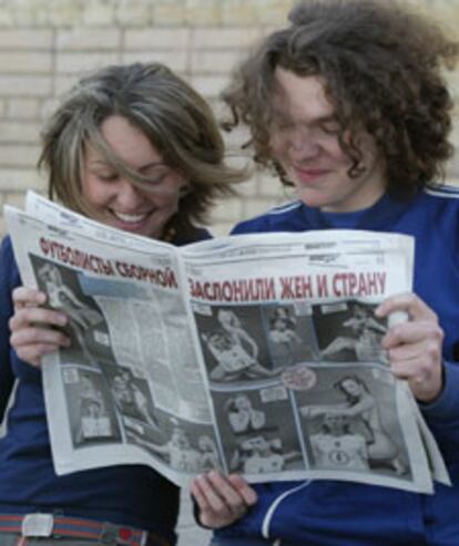 Una pareja sonríe mientras lee el <i>Komsomolskaya Pravda, </i>en el que las mujeres de los futbolistas rusos aparecen desnudas.