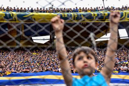 Un niño en La Bombonera y, de fondo, la afición de Boca Juniors.