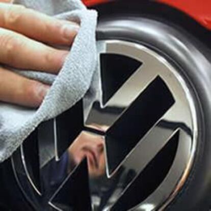 Un hombre limpia el logo de la marca alemana de coches.
