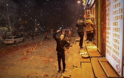 Un hombre toma una fotografía de los fuegos artificiales en las calles de Pekín (China).