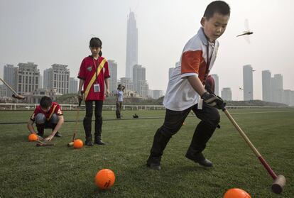 El joven jugador chino Dong Jialin, a la derecha, practica con el palo y la pelota durante el campamento de verano del Goldin Metropolitan de Tianjin, China.
