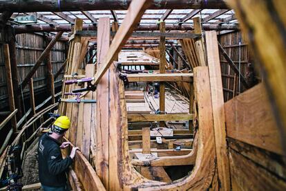 Un operario cubre con tablones la estructura del galeón.