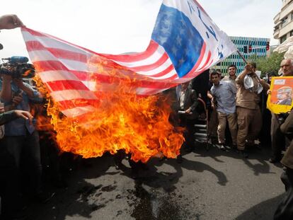 Manifestantes iraníes prenden fuego a una bandera improvisada de los EE. UU. durante una manifestación en Teherán. 