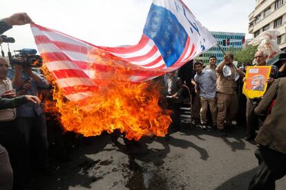 Manifestantes iraníes prenden fuego a una bandera improvisada de los EE. UU. durante una manifestación en Teherán. 