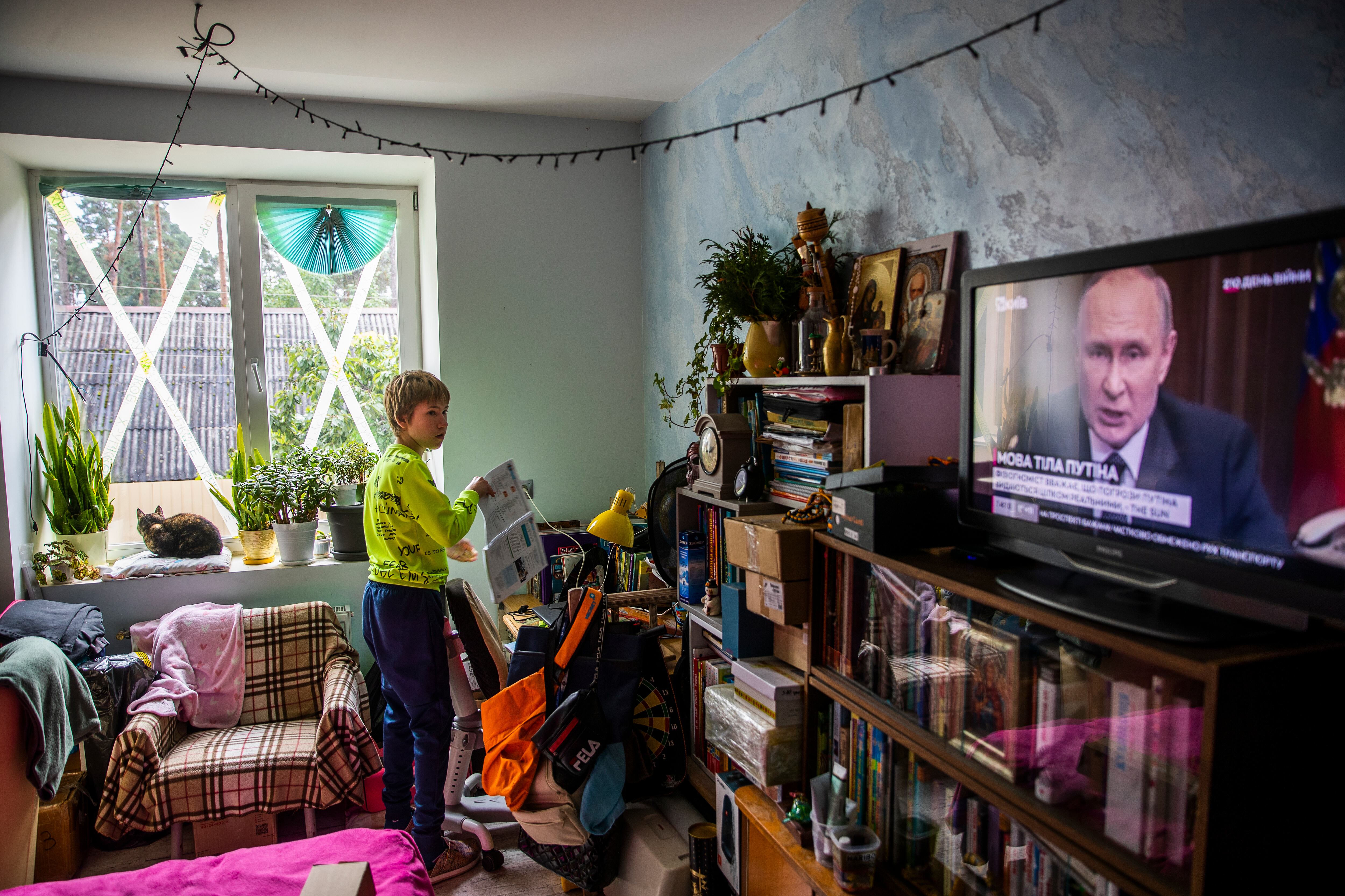 Misha, junto a su escritorio mientras observa en un canal de noticias una intervención del presidente ruso, Vladímir Putin. 