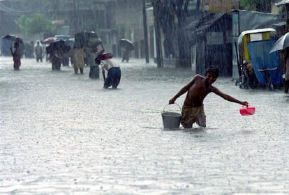 Un niño lleva un cubo de agua potable por una calle inundada de Calcuta (India). La ciudad, muy afectada por las inundaciones y en permanente riesgo de huracanas, es la quinta más amenazada por tsunamis.