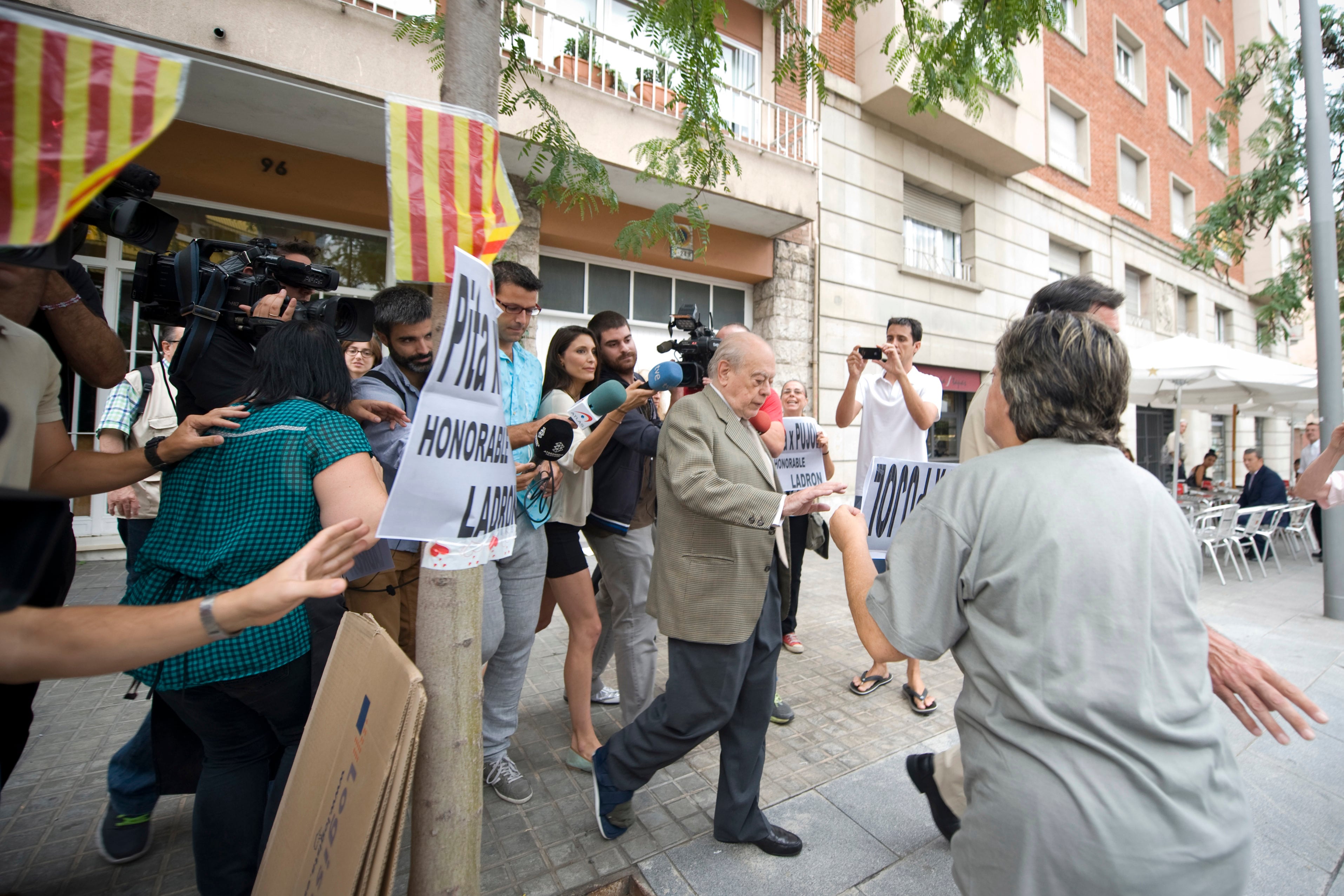 Jordi Pujol, expresidente de la Generalitat de Cataluña, sale de su residencia rodeado de personas con carteles en los que le llaman ladrón, en julio de 2014.