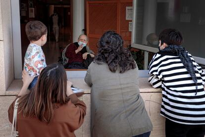 Una anciana recibe la visita de sus familiares a través de una ventana de su residencia en Valencia.