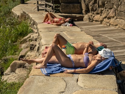 Varias personas disfrutan de las altas temperaturas en las termas de O Muiño y la zona fluvial del río Miño, este jueves en Ourense.