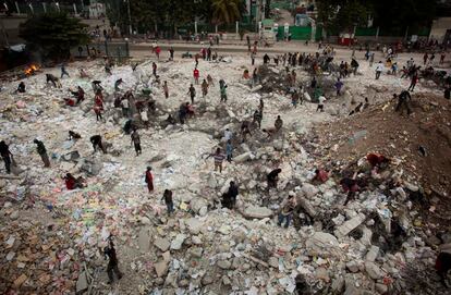 Varios hombres intentan extraer trozos de hierro de los cimientos de un edificio derruido de Port-au-Prince, con el objetivo de venderlo posteriormente. 1 de octubre de 2010.
