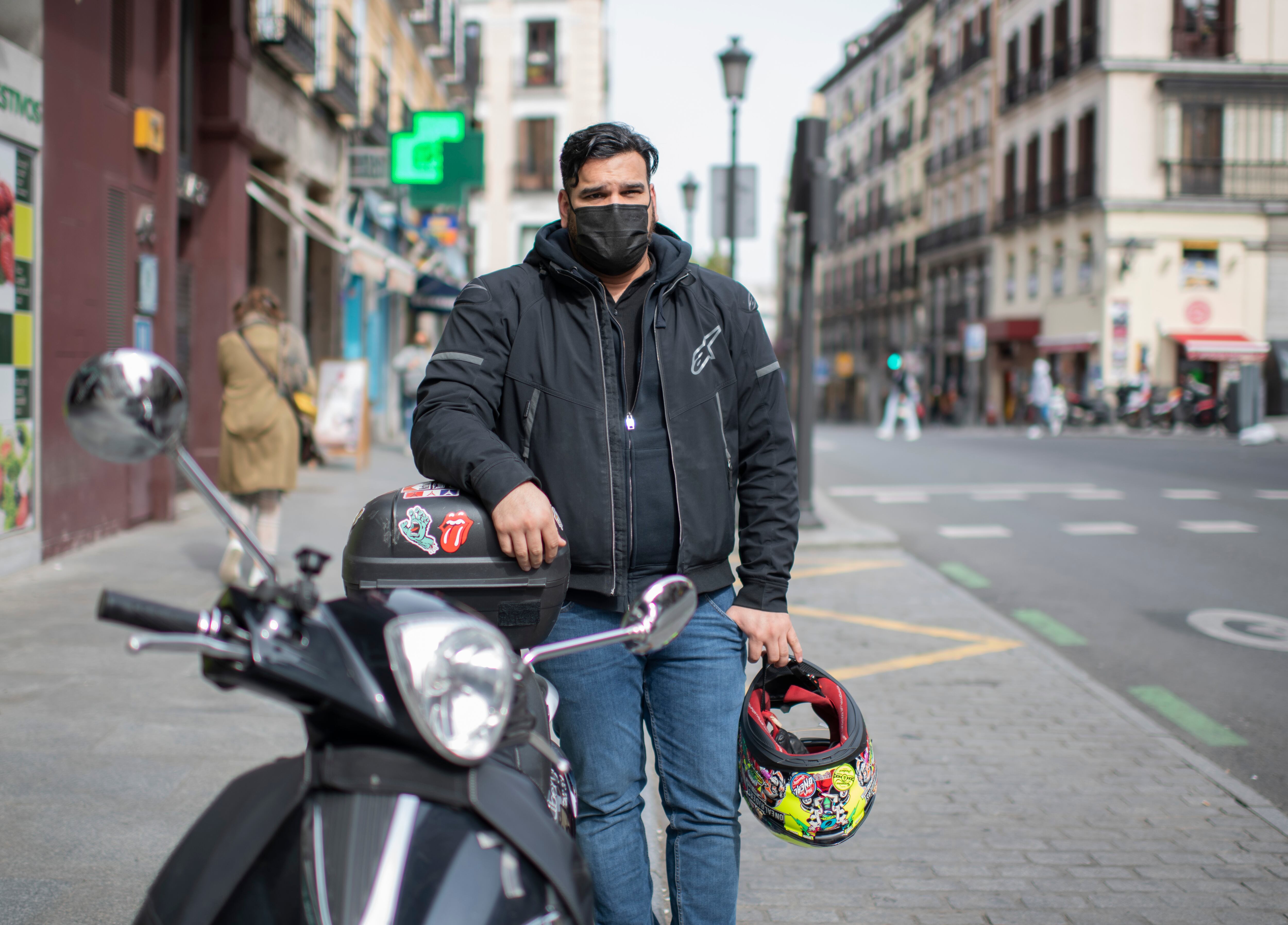 Marco Pérez, en una calle de Madrid con la moto en la que reparte comida.