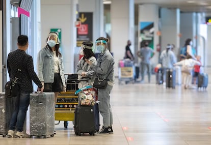 Varias personas protegidas con mascarillas y pantallas protectoras, en la terminal T1 del Aeropuerto Adolfo Suárez Madrid-Barajas el 1 de julio.