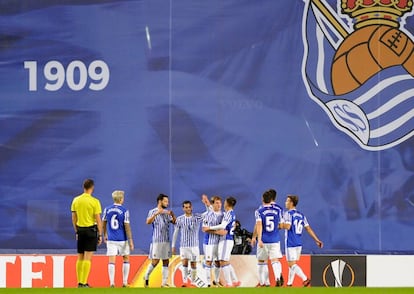 Jugadores de la Real Sociedad celebran un gol ante la lona que tapa las obras en el estadio de Anoeta.